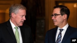Treasury Secretary Steven Mnuchin and White House chief of staff Mark Meadows look to each other as they speak to reporters on Capitol Hill in Washington, Aug. 6, 2020. 