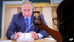 Journalists watch a TV broadcast showing Russian President Vladimir Putin at the St. Petersburg International Economic Forum, in St. Petersburg, Russia, June 6, 2019.