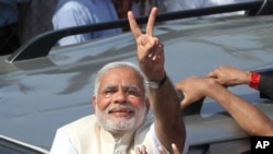 India's main opposition Bharatiya Janata Party’s prime ministerial candidate Narendra Modi displays the victory symbol to supporters after casting his vote in Ahmadabad, India, April 30, 2014.
