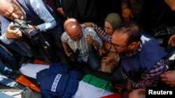 Waombolezaji wakiwa pembeni ya mwili wa marehemu Shireen Abu Akleh, mwandishi wa habari wa Al Jazeera ambaye inadaiwa aliuawa katika mashambulizi ya bunduki wakati Israeli ilipovamia eneo hilo la Wapalestina.huko Jenin May 11, 2022. REUTERS/Mohamad Torokman