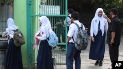 Petugas keamanan memeriksa suhu tubuh para siswa sebelum mereka memasuki halaman sekolah mereka di Bekasi, pinggiran Jakarta, 13 Juli 2020. (Foto: dok)