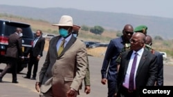 Rais wa Uganda Yoweri Museveni (kushoto) na rais wa Tanzania John Magufuli (kulia) wakielekea katika mojawapo ya vikao kuhusu ujenzi wa bomba la mafuta kutoka Hoima hadi Tanga