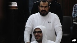 លោក Mohammed Soltan ត្រូវបានរុញ​ដោយ ឪពុករបស់លោកឈ្មោះ Salah ក្នុងអំឡុងពេល បង្ហាញខ្លួនក្នុងតុលាការមួយ នៅក្នុងទីក្រុង Le Caire ប្រទេសអេហ្ស៊ីបនាថ្ងៃទី០៩ ខែមិនា ឆ្នាំ២០១៥។