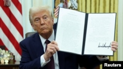 Президент Дональд Трамп подписывает исполнительные указы в Овальном кабинете Белого дома, 23 января 2025 года. REUTERS/Kevin Lamarque.