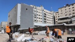 Des ouvriers nettoient les déchets d'une route de la ville de Gaza, dans le centre de la bande de Gaza, le 28 février 2025