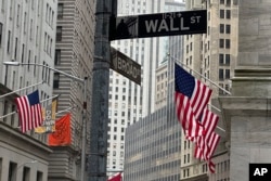 ARCHIVO - Banderas estadounidenses cuelgan de la fachada de la Bolsa de Valores de Nueva York, a la derecha, el 11 de abril de 2024, en Nueva York. (Foto AP/Peter Morgan)
