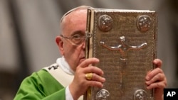 Pope Francis hoists the Gospel book as he celebrates a mass in St. Peter's Basilica at the Vatican, Oct. 5, 2014, to open the extraordinary Synod on the family.