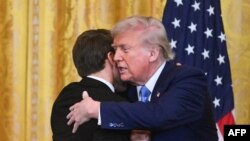 Дональд Трамп и Эммануэль Макрон завершают пресс-конференцию в Белом доме дружескими объятиями. 24 февраля 2025 года. (Photo by ROBERTO SCHMIDT / AFP).