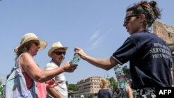 Members of the Italian Civil Protection (Protezione Civile) give water bottles to people and tourists in front of the Ancient Colosseum in central Rome. Italy experienced a heatwave in August 2018. (AFP PHOTO / Andreas SOLARO)