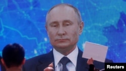 អ្នកយកព័ត៌មាន អង្គុយ​នៅមុខ​​អេក្រង់​ក្នុងអំឡុង​ពេល​សន្និសីទ​សារព័ត៌មាន​ប្រចាំឆ្នាំ​របស់​ប្រធានាធិបតី​រុស្ស៊ី​លោក Vladimir Putin ដែល​បាន​ធ្វើឡើង​តាម​អនឡាញ​ក្នុង​ទម្រង់​សន្និសីទ​វីដេអូ នៅ​ទីក្រុង​មូស្គូ នៅ​ថ្ងៃទី១៧ ខែធ្នូ ឆ្នាំ២០២០។