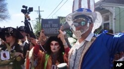 Costumed revelers gather Monday, March 4, 2019, for the annual Krewe of Red Beans march in New Orleans. (AP Photo/Kevin McGill)