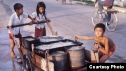 Cambodian children transfer water to their home in Phnom Penh, Cambodia, file photo from 1980's. (Courtesy of John Burgess)