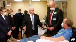 Vice President Mike Pence, center, visits Dennis Nelson, a patient who survived the coronavirus and was going to give blood, during a tour of the Mayo Clinic Tuesday, April 28, 2020.