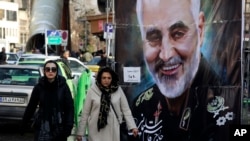 Women walk past a banner of Iranian Revolutionary Guard Gen. Qassem Soleimani, who was killed in Iraq in a U.S. drone attack Friday, in Tajrish square in northern Tehran, Iran, Jan. 9, 2020.