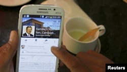 FILE PHOTO: A person uses a smartphone to look at the Facebook page of Cambodia's Prime Minister Hun Sen, during breakfast at a restaurant in central Phnom Penh, Cambodia October 7, 2015. (REUTERS/Samrang Pring)