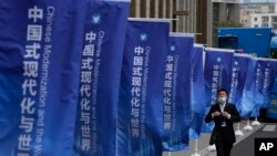 一名男子走過上海街頭插滿的宣傳旗幟：「中國式現代化與世界」。 （2023年4月21日）