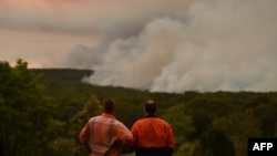 បុរសពីរនាក់កំពុងឈរមើលភ្លើងឆេះព្រៃនៅក្រុង Bargo ប្រទេសអូស្រ្តាលី កាលពីថ្ងៃទី១៩ ខែធ្នូ ឆ្នាំ២០១៩។ 