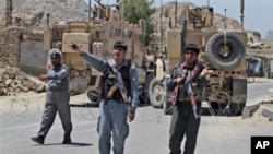 Afghan policemen and armored NATO military vehicles stand guard close to the main prison in Kandahar, south of Kabul, Afghanistan, April 25, 2011