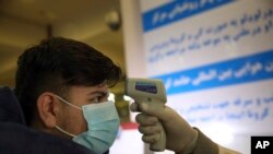 An Afghan health worker takes the temperature of a passenger as a preventive measure for Coronavirus, during screening of travelers who arrived from China, at the Hamid Karzai International Airport in Kabul, Afghanistan, Monday, Feb. 3, 2020…