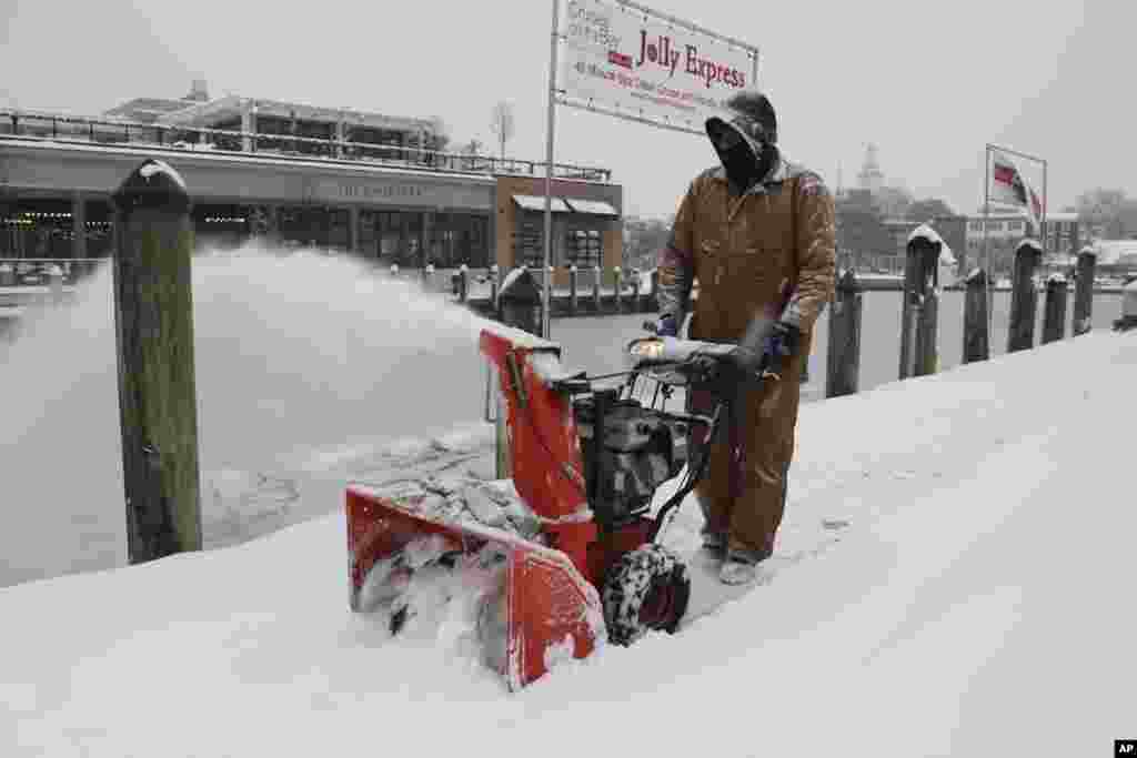 Tony Savage, who works for the city of Annapolis, clears snow along the City Dock in Annapolis, Maryland, Jan. 6, 2025.