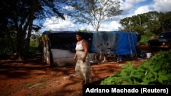 Tatiana Araujo de Sirqueira, 33, says she stopped receiving coronavirus emergency aid. She stands near her home on squatted land near Planalto Palace in Brasilia, March 3, 2021. (REUTERS/Adriano Machado)