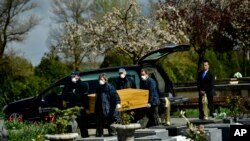 Undertakers wearing protection masks to protect from the coronavirus, carry a coffin to a burial at Salvador cemetery during the coronavirus outbreak, near to Vitoria, northern Spain, Monday, March 30, 2020. 