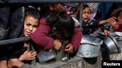 Niños palestinos esperan recibir comida cocinada en una cocina benéfica en medio de escasez de alimentos, mientras continúa el conflicto entre Israel y el grupo islamista palestino Hamás, en Rafah, en el sur de la Franja de Gaza, el 20 de febrero de 2024.