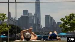 Wadansu mutane kwance kan ziyawa a bakin rafi sabili da zafi a birnin New York