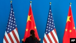 រូបភាពឯកសារ៖ ស្ត្រីជនជាតិចិនម្នាក់​កំពុង​រៀបទង់ជាតិចិន និង​ទង់ជាតិ​អាមេរិក​នៅ​ក្បែរ​គ្នា។ 