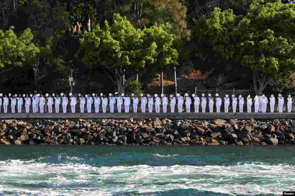 Crew members salute on the day Britain's King Charles and Queen Camilla conduct an Australian Navy fleet review in Sydney Harbour during a visit to Sydney.