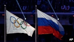 FILE - The Russian national flag (R) flies next to the Olympic flag during the closing ceremony of the 2014 Winter Olympics in Sochi, Russia, Feb. 23, 2014. A