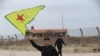 A Syrian Kurd waves the flag of YPG (People's Protection Units) near Qamishli's airport in northeastern Syria on December 8, 2024, following the fall of the capital Damascus to anti-government fighters.