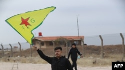 A Syrian Kurd waves the flag of YPG (People's Protection Units) near Qamishli's airport in northeastern Syria on December 8, 2024, following the fall of the capital Damascus to anti-government fighters.