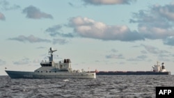 FILE - The Chinese ship, the bulk carrier Yi Peng 3, right, is anchored and being monitored by a Danish naval patrol vessels in the sea of Kattegat, near the City og Granaa in Jutland, Denmark, Nov. 20, 2024.