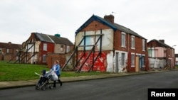 FILE - A woman pushes a stroller along a semi-derelict street in the Gresham area of Middlesbrough, northern Britain, Jan. 20, 2016. Asylum seekers in the northern English town of Middlesbrough are often suffering abuse.