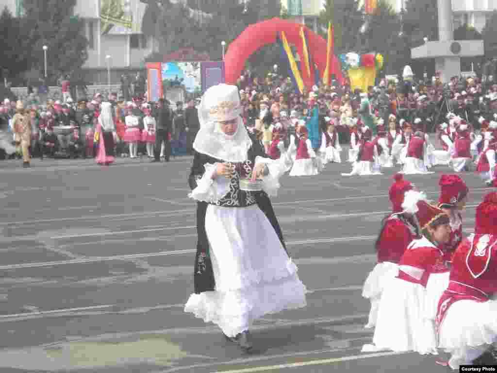 Milliy kiyimdagi qirg'iz ayoli qo'lida uyg'onish ramzi bo'lgan bahor taomi bilan.