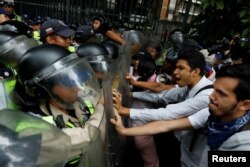 FILE - Opposition supporters confront riot security forces while rallying against President Nicolas Maduro in Caracas, Venezuela, May 12, 2017.