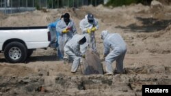 Trabajadores del cementerio público en San Salvador, El Salvador entierran el féretro con una persona fallecida por COVID-19. El 3 de agosto de 2020.