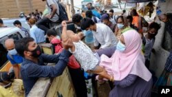 A child is handed over to board a ferry as people crowd a ferry terminal to leave the city ahead of a lockdown set to start on July 1, in Munshiganj, on the outskirts of Dhaka, Bangladesh, Wednesday, June 30, 2021. (AP Photo/Mahmud Hossain Opu)
