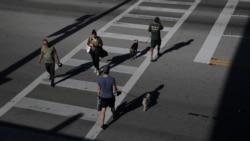 Gente cruzando una calle de Miami Beach y practicando la "distancia social", la medida impuesta por las autoridades para frenar la propagación del coronavirus.