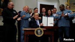 U.S. President Donald Trump, surrounded with American workers, shows a proclamation to establish tariffs on imports of steel and aluminum at the White House in Washington, March 8, 2018. (REUTERS/Leah Millis)