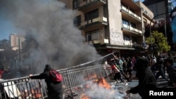 Los manifestantes mueven una cerca para usarla como barricada durante una protesta en Concepción, Chile.