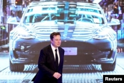 FILE PHOTO: Tesla Inc CEO Elon Musk walks next to a screen showing an image of Tesla Model 3 car during an opening ceremony for Tesla China-made Model Y program in Shanghai