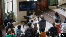 Massachusetts Institute of Technology students gather around a monitor in an overflow area on the MIT campus to watch an update by scientists on the discovery of gravitational waves, Thursday, Feb. 11, 2016,