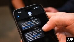 Muškarac pokazuje dvije poruke na svom mobilnom telefonu: "Vaš pasoš i lična karta su spremni" i "Izdavanje dokumenata obustavljeno iz tehničkih razloga"