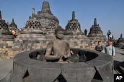 Para turis melihat-lihat patung Buddha di Candi Prambanan di Magelang, Jawa Tengah, 12 Agustus 2019. (Foto: AP/Slamet Riyadi)