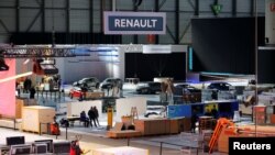 FILE - Cars and workers are pictured at the Palexpo exhibition centre as the 90th edition of the International Motor Show is cancelled to curb the spread of the coronavirus, in Geneva, Switzerland, Feb. 28, 2020.
