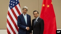 FILE - U.S. Secretary of State John Kerry, left, shakes hands with Chinese Foreign Minister Wang Yi as they pose for photos before their meeting at the 47th ASEAN Foreign Ministers' Meeting in Naypyitaw, Myanmar, Aug. 9,2014.