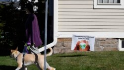 A woman walks her dog past a sign supporting equity in schools, in Guilford, Conn., on Tuesday, Oct. 19, 2021. (AP Photo/Jessica Hill)