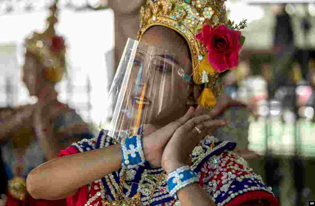 A Thai classical dancer wearing face shield to help curb the spread of the coronavirus performs at the Erawan Shrine in Bangkok, Thailand.
